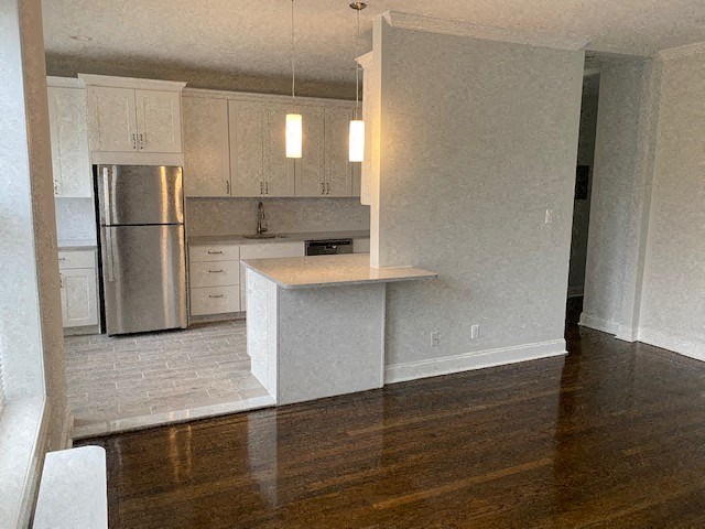 an empty kitchen with white cabinets and a refrigerator