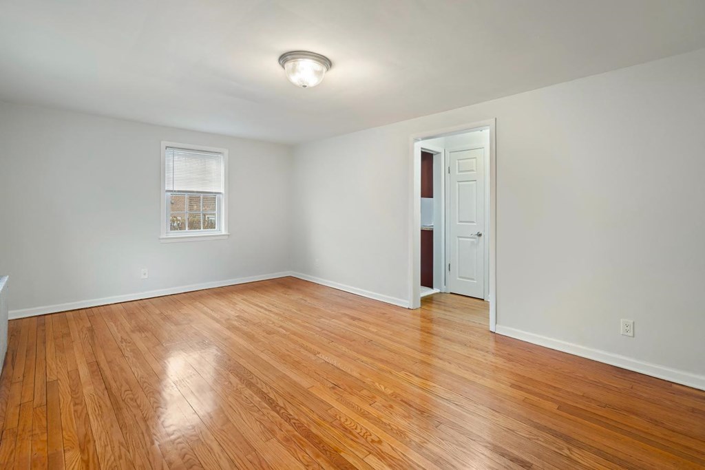 an empty living room with wood floors and a door to a closet
