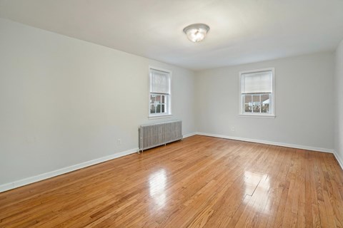 an empty living room with a hardwood floor and a window