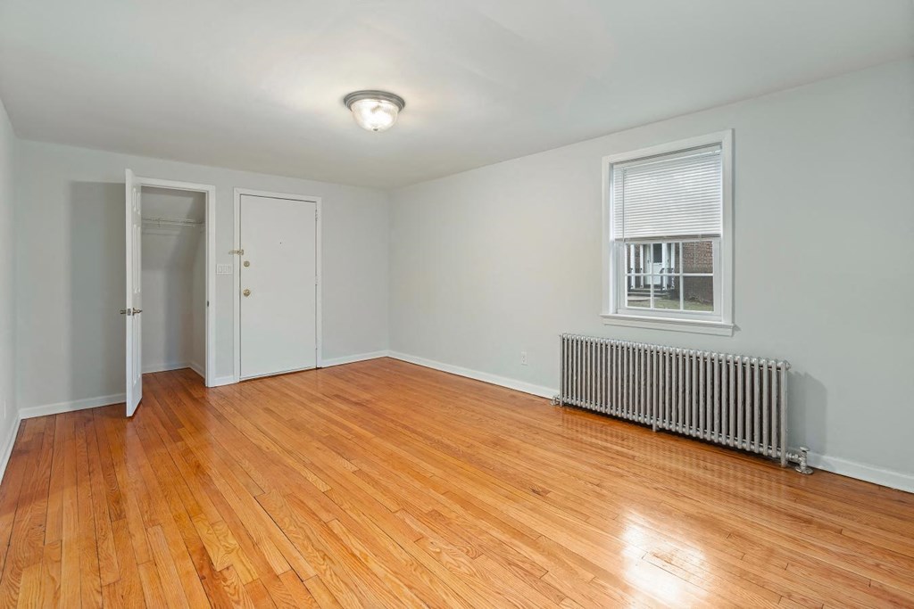 an empty living room with wood floors and a radiator