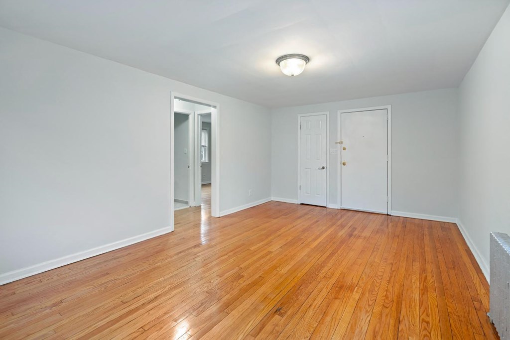 an empty living room with wood floors and white walls