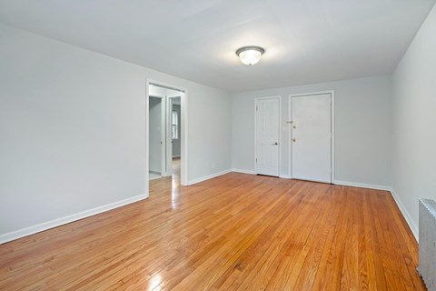 an empty living room with wood floors and white walls