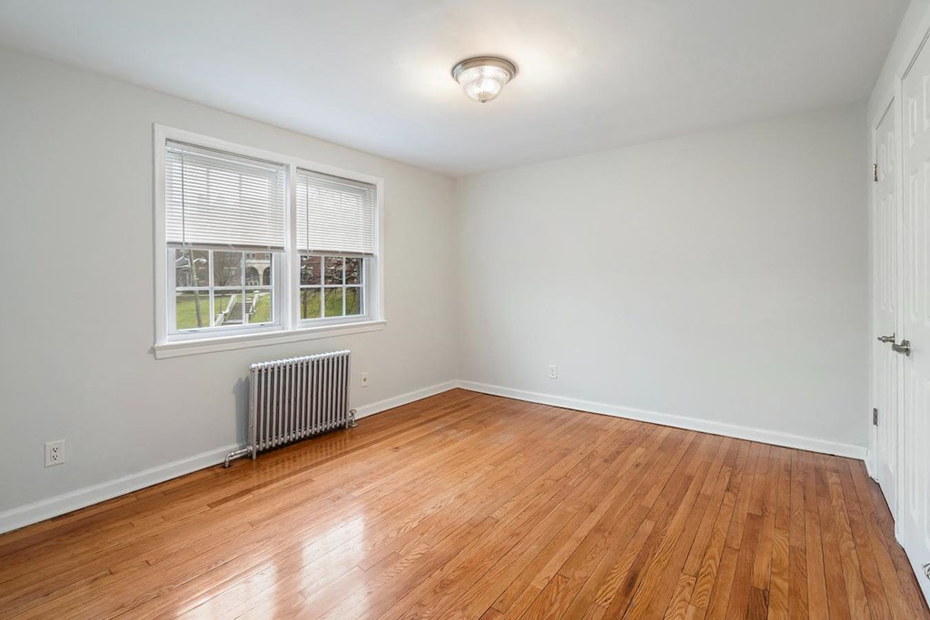 an empty living room with wood floors and a window
