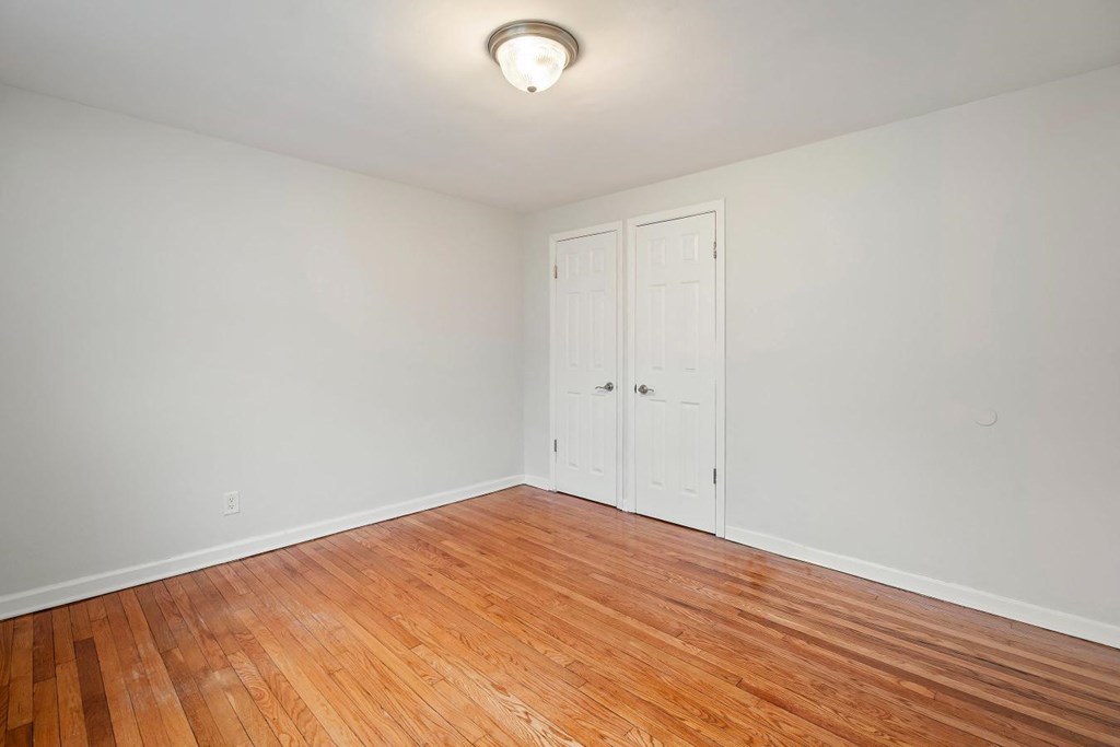 an empty living room with wood flooring and two doors