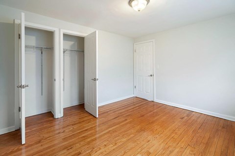 an empty bedroom with wood floors and closet doors