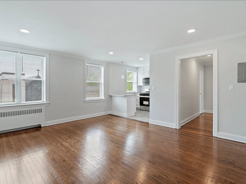 A spacious room with wooden floors and white walls.