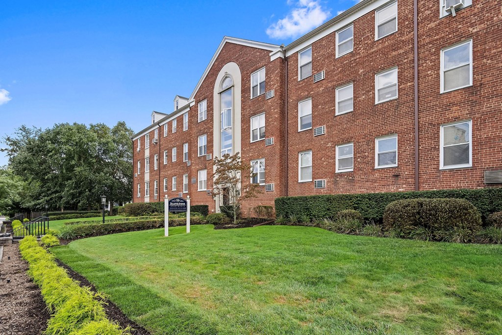 a large brick building with a green lawn in front of it