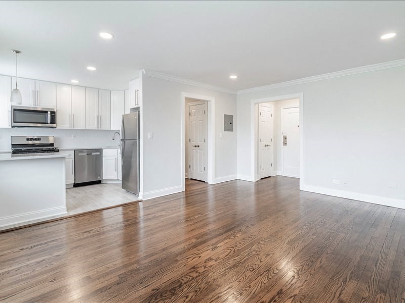 A kitchen with white cabinets and a wooden floor.