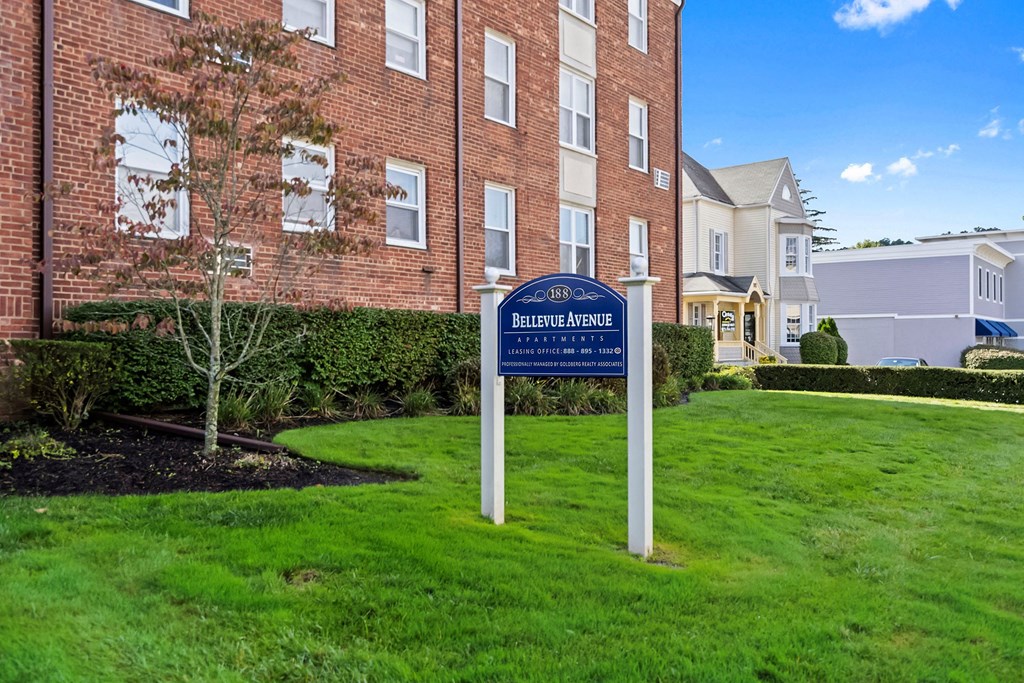 a blue and white sign in the grass in front of a brick building