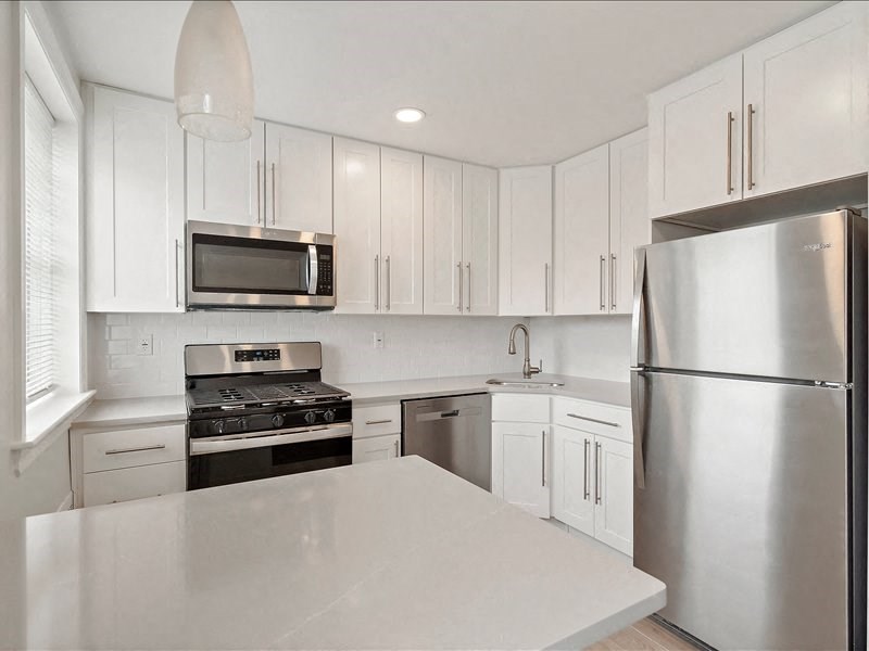 A modern kitchen with white cabinets and stainless steel appliances.