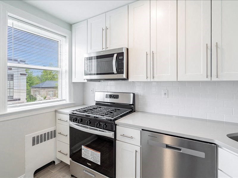 A kitchen with white cabinets and a stainless steel dishwasher.