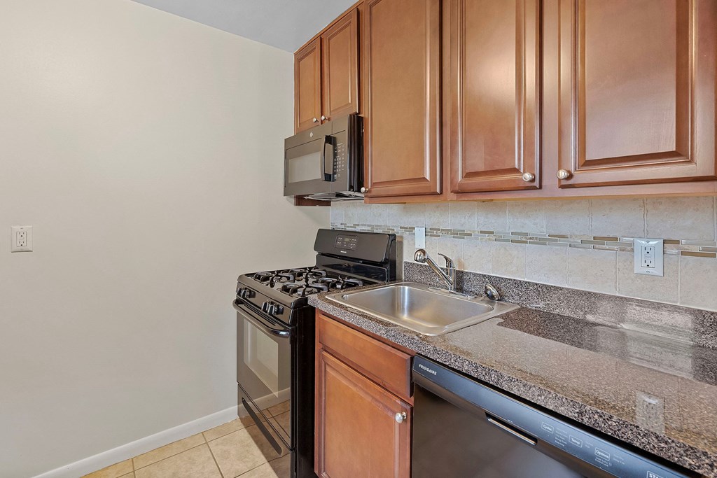 a kitchen with a sink stove and microwave and wooden cabinets