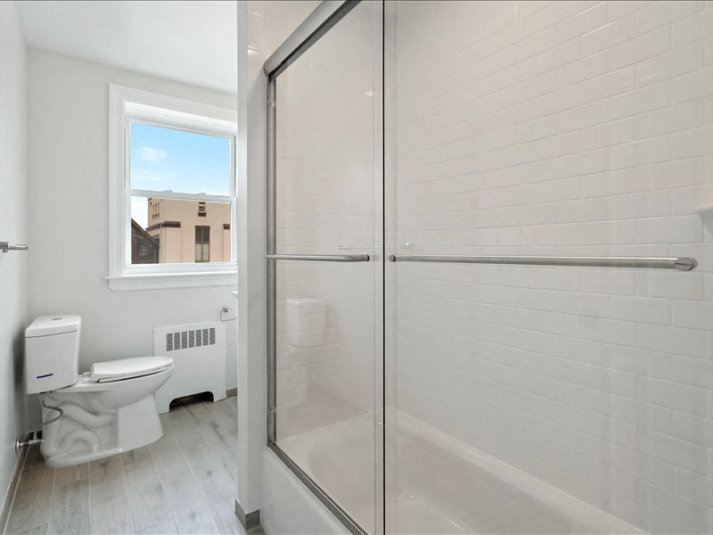 A white bathroom with a toilet, sink, and a window.