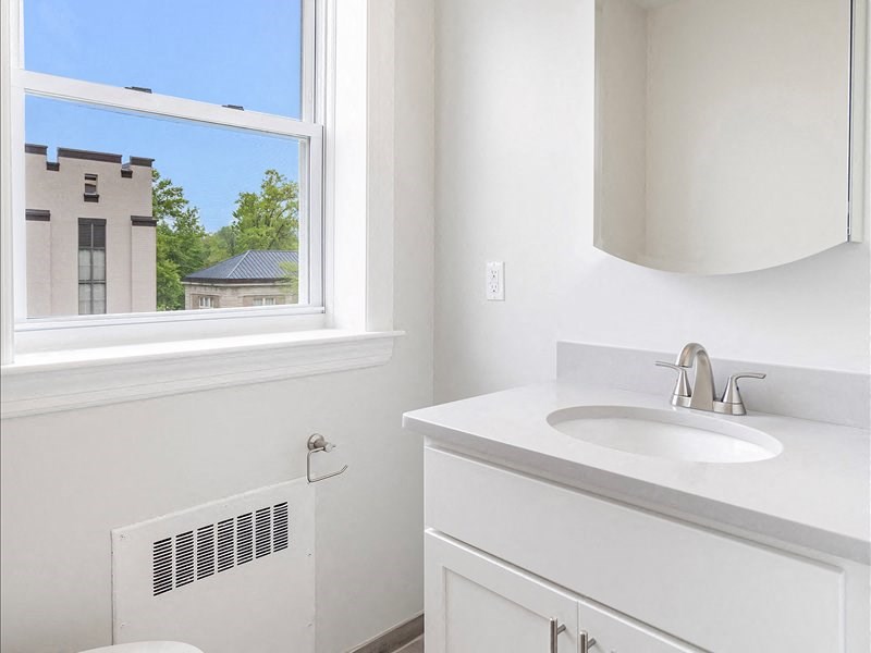 A white bathroom with a window and a sink.