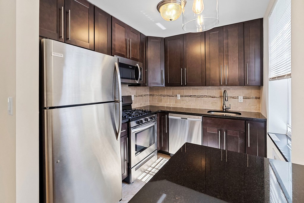 a kitchen with stainless steel appliances and dark wood cabinets