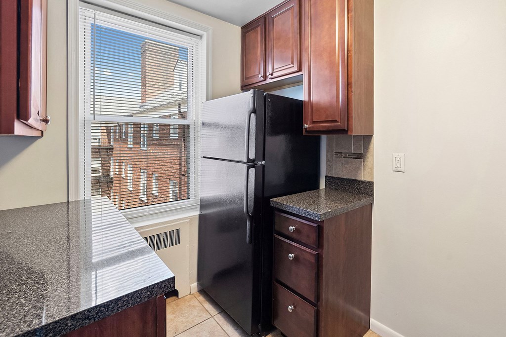a kitchen with a window and a black refrigerator