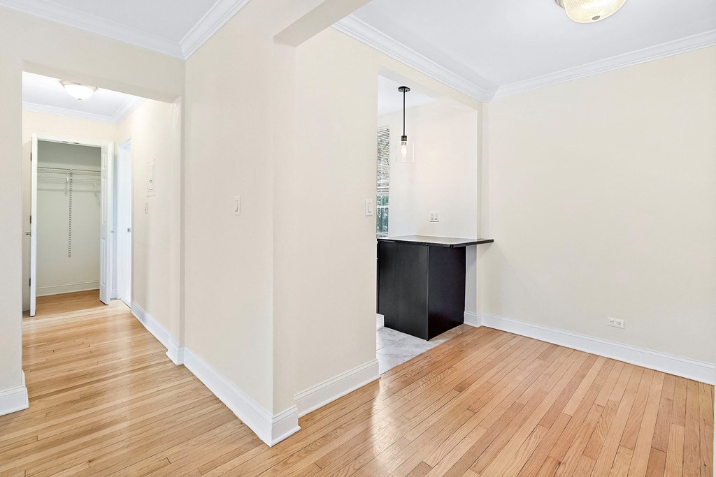 a renovated living room and dining room with white walls and wood floors