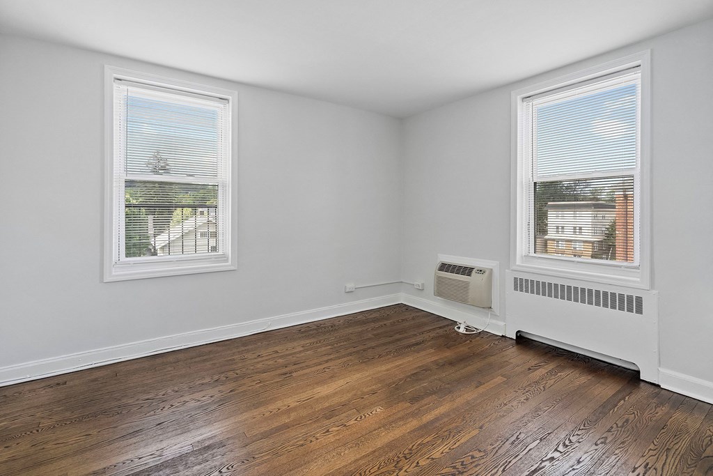 the living room of an empty house with wood flooring and two windows