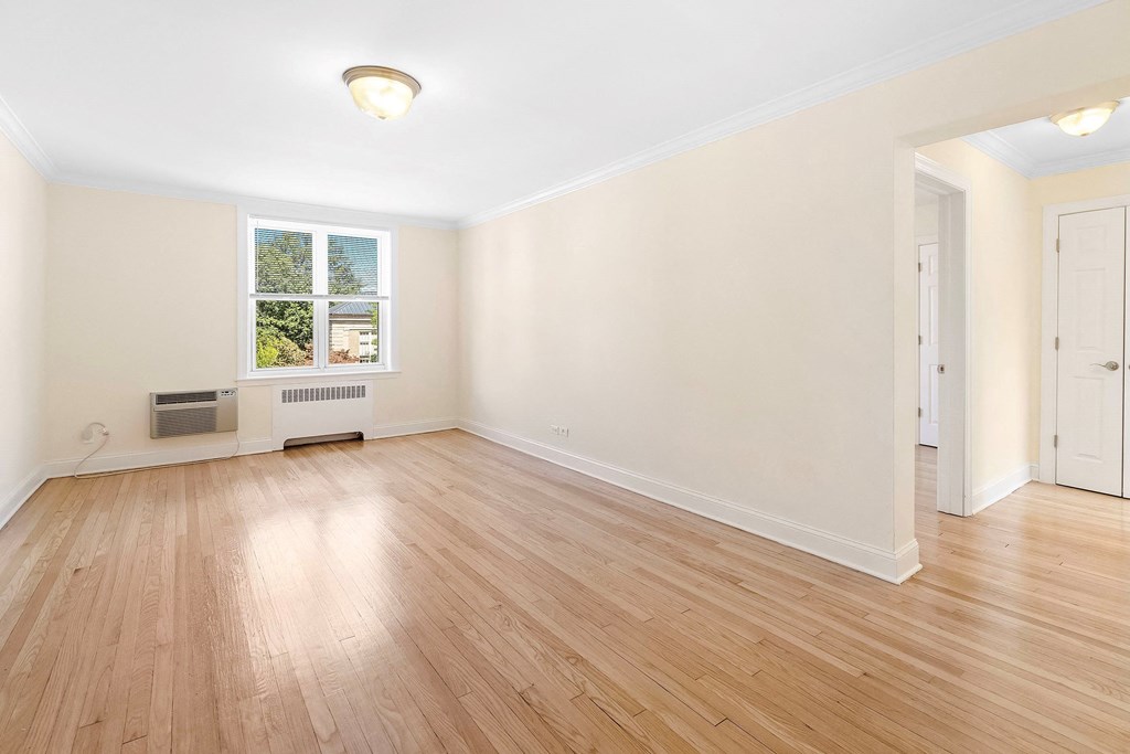 an empty living room with wood flooring and a window