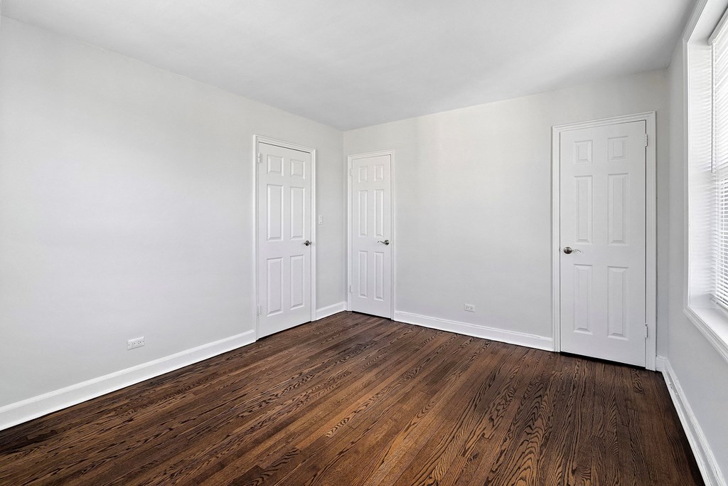 an empty room with white walls and wooden floors and two doors