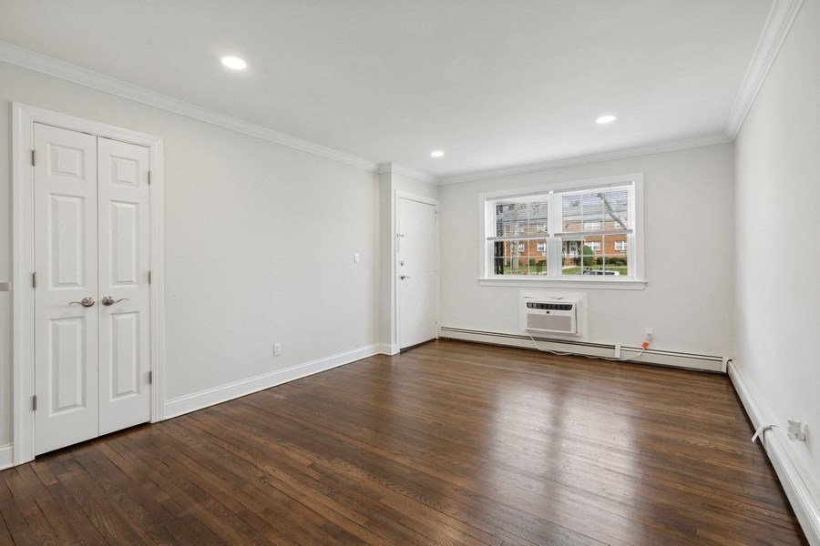 a living room with white walls and wooden floors and a window
