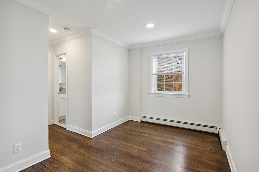 a living room with white walls and a window and wooden floors