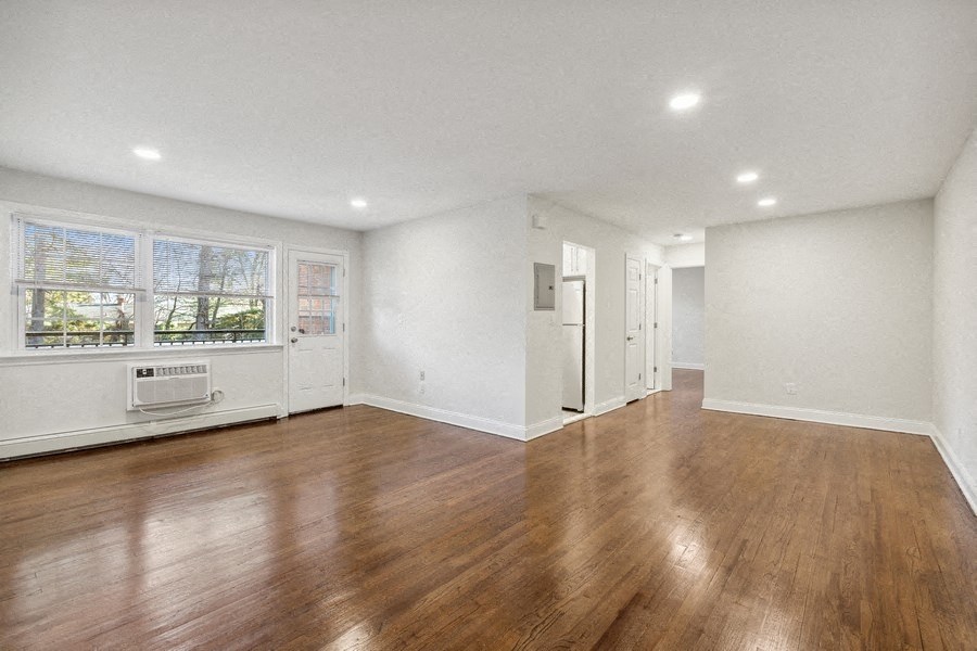 an empty living room with white walls and wood floors