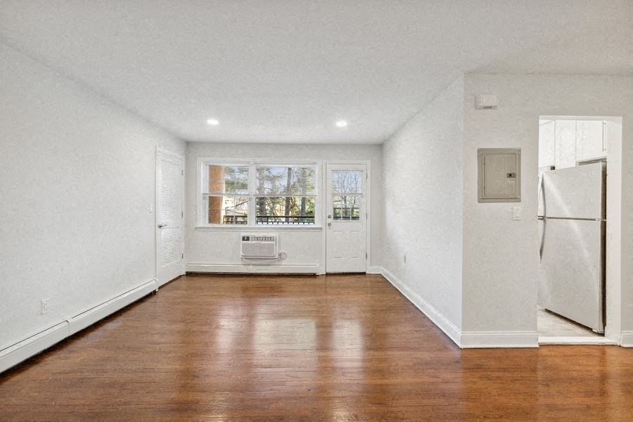 an empty living room with a refrigerator and a window