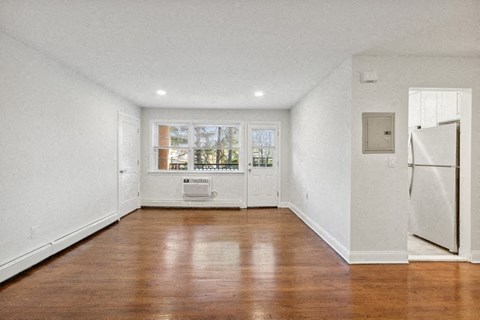 an empty living room with a refrigerator and a window