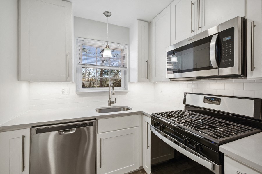 a kitchen with white cabinets and stainless steel appliances and a microwave