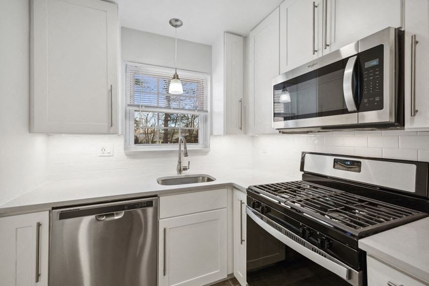a kitchen with white cabinets and stainless steel appliances and a microwave