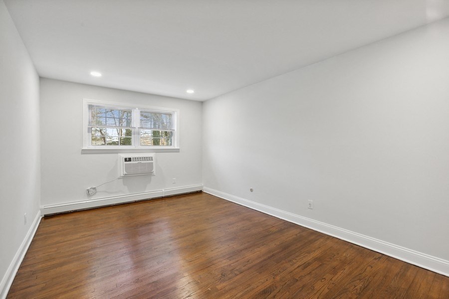 a living room with white walls and wooden floors and a window