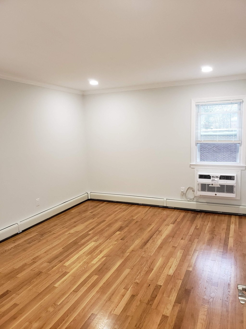 an empty room with wooden floors and a window
