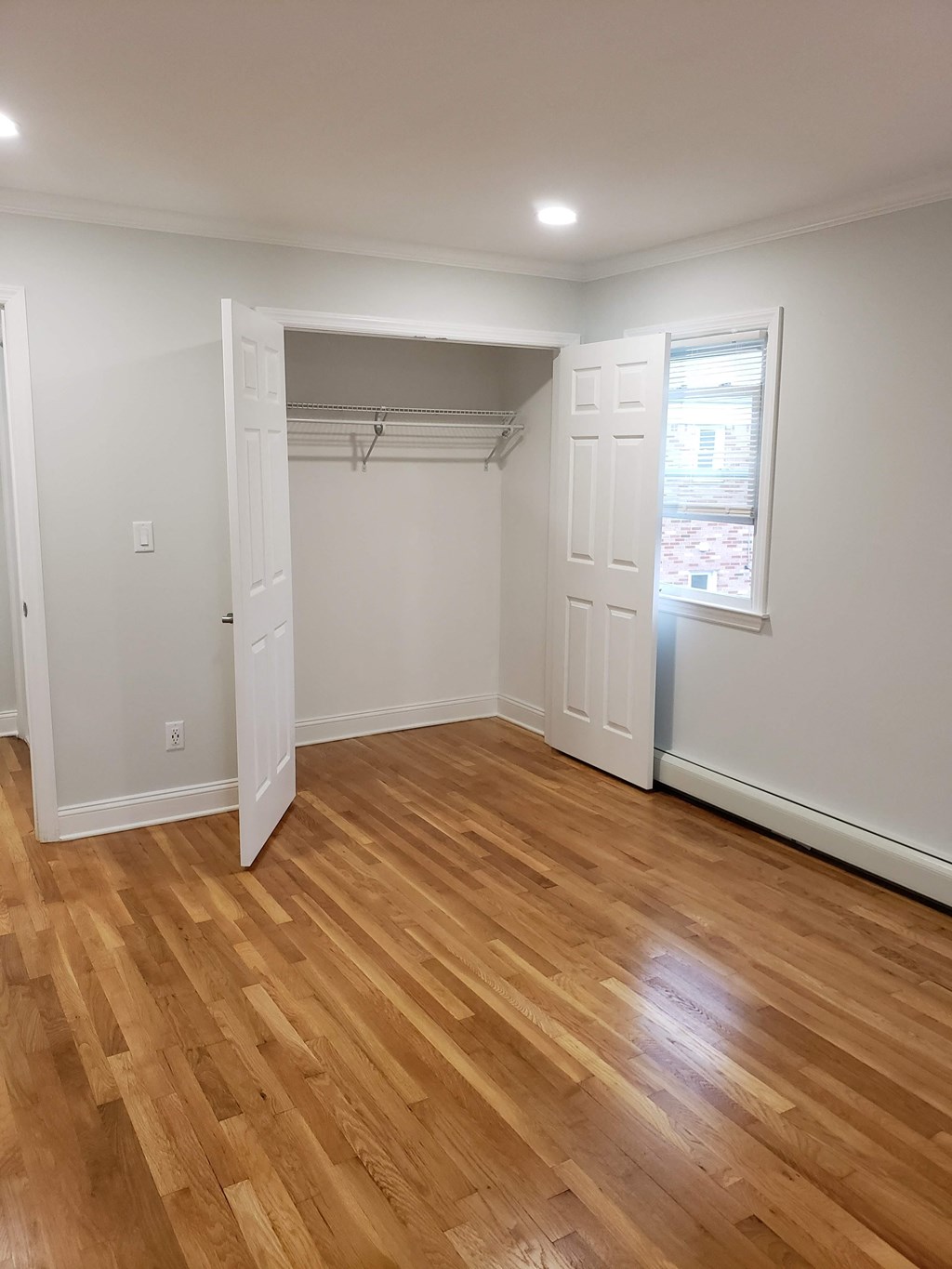 a living room with a wooden floor and a closet with a window