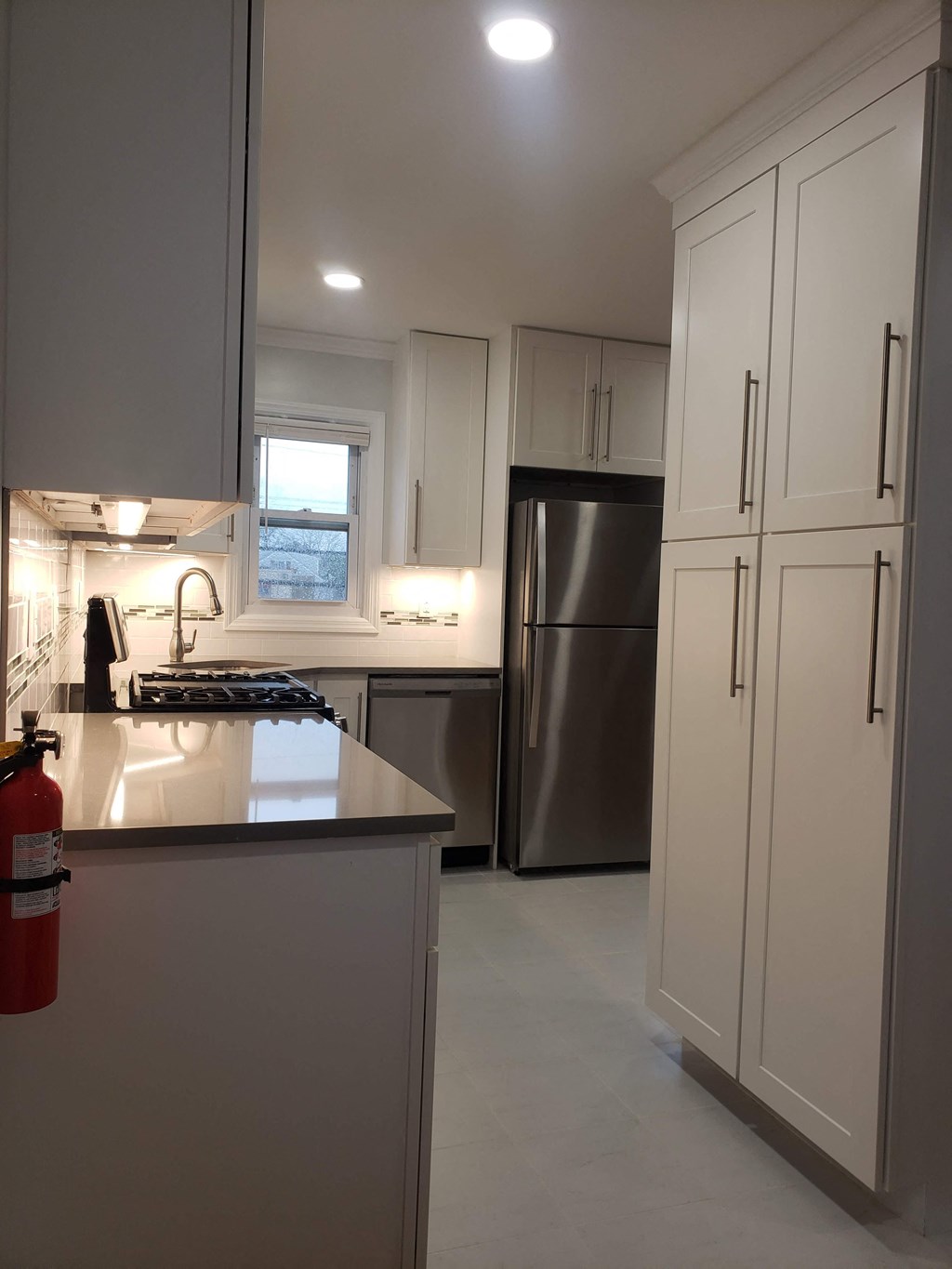 a white kitchen with stainless steel appliances and white cabinets