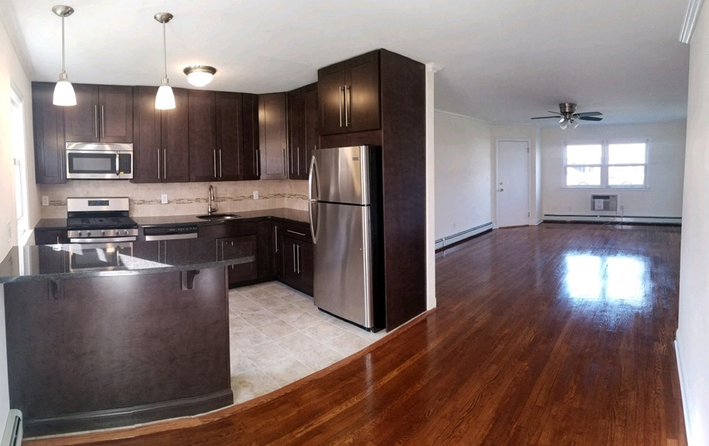 an empty kitchen with wooden floors and stainless steel appliances
