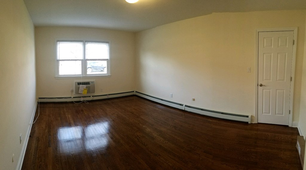 an empty living room with white walls and a wooden floor