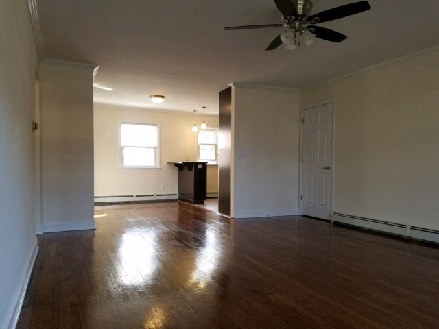 an empty living room with wood floors and a ceiling fan