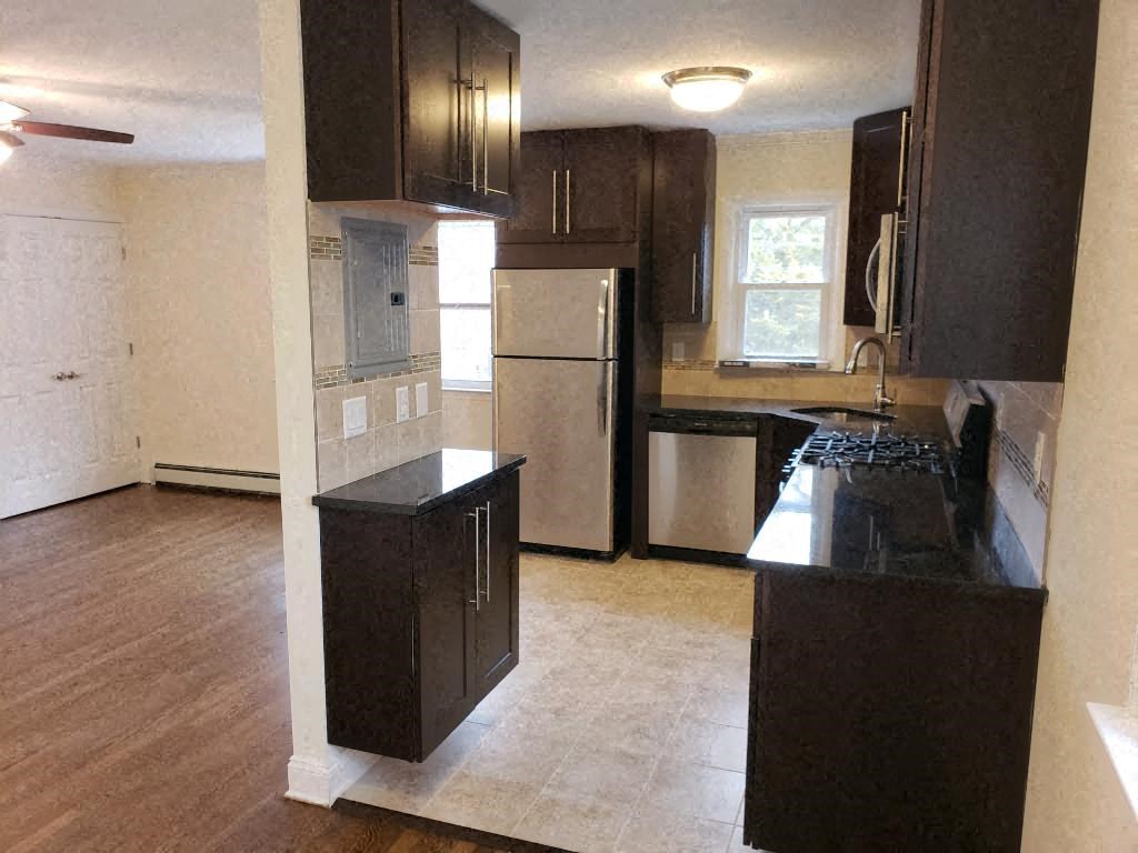 an empty kitchen with black cabinets and stainless steel appliances