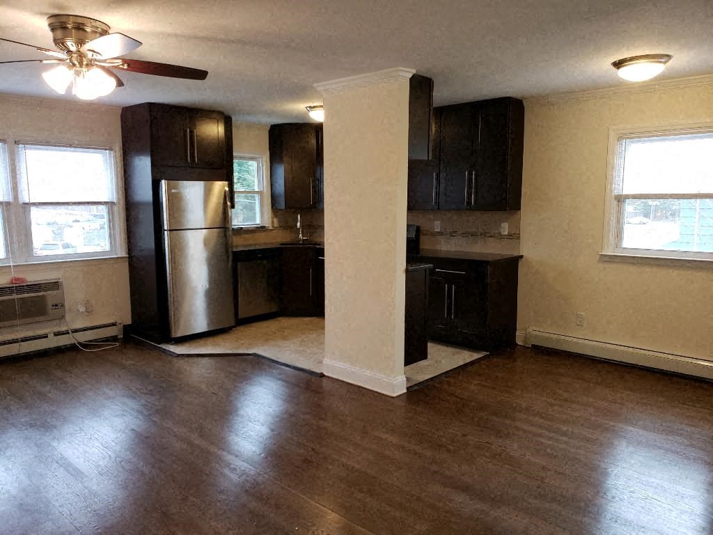 an empty kitchen with wood floors and a refrigerator