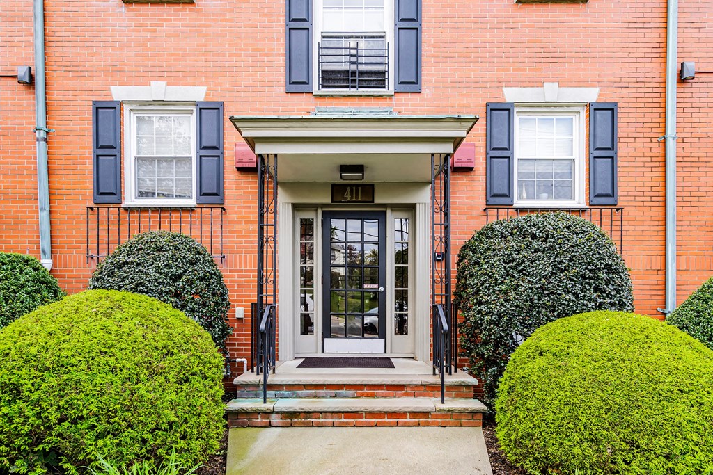 the front of a red brick house with blue shutters and a door