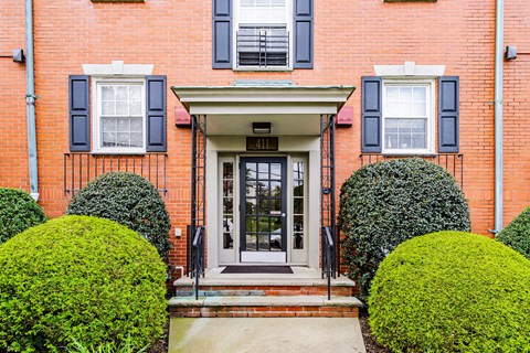 the front of a red brick house with blue shutters and a door