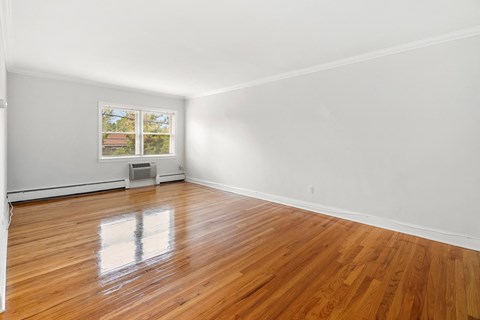 an empty living room with wood floors and a window