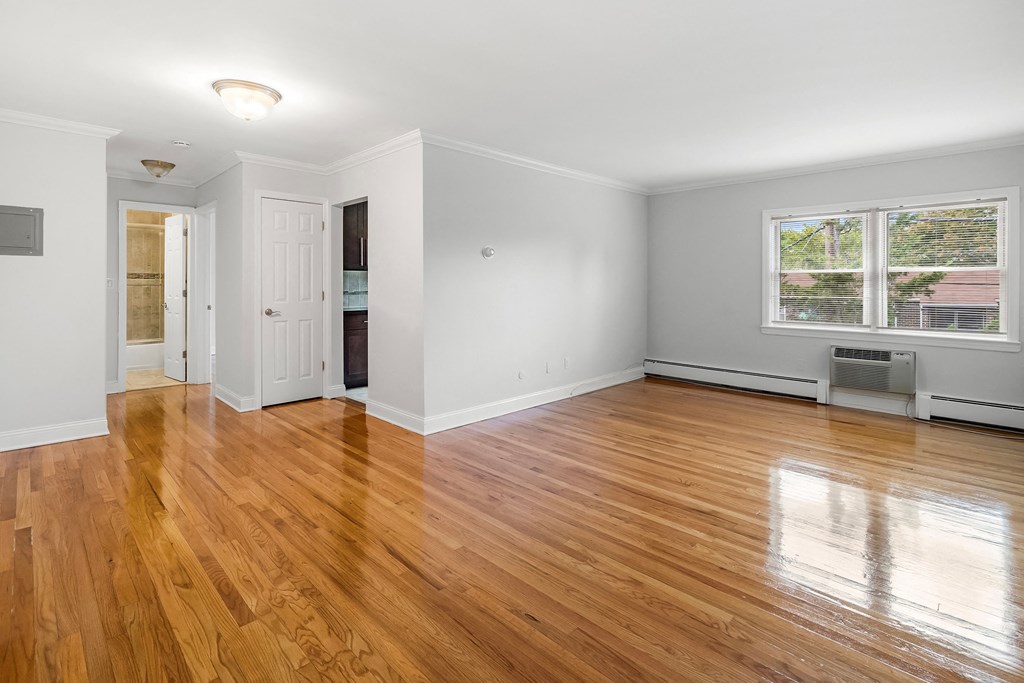 an empty living room with wood floors and a window