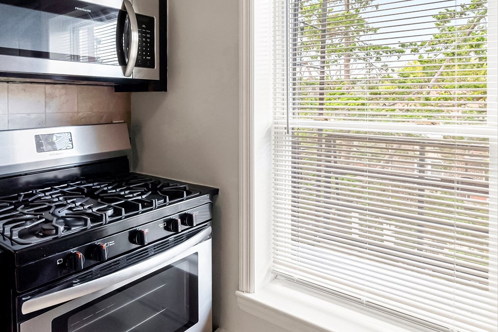 a kitchen with a stove and a microwave and a window