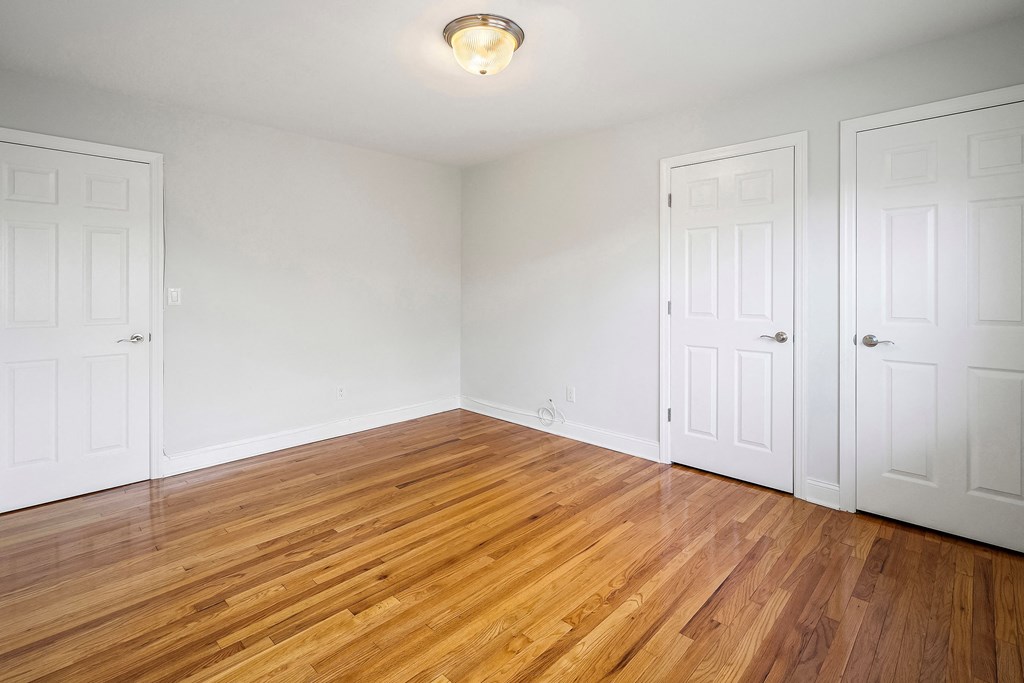a bedroom with two closets and a wood floor