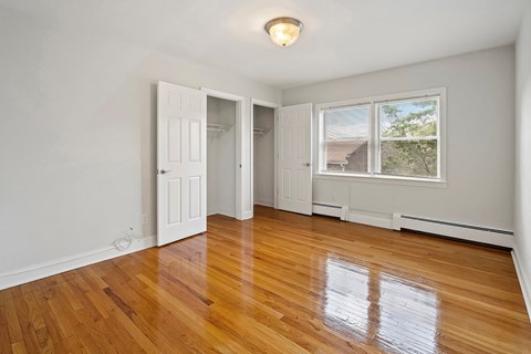 an empty living room with wood floors and white walls