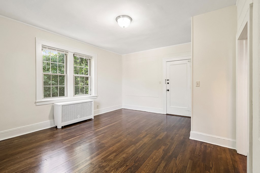 an empty living room with wood floors and white walls