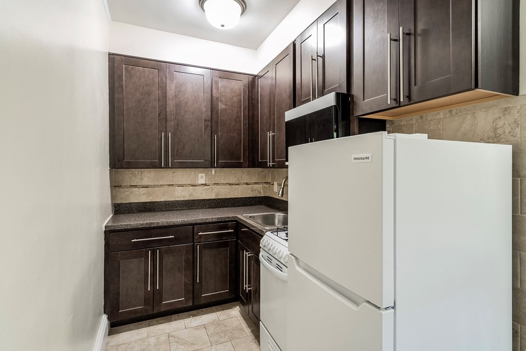 a kitchen with dark wood cabinets and a white refrigerator