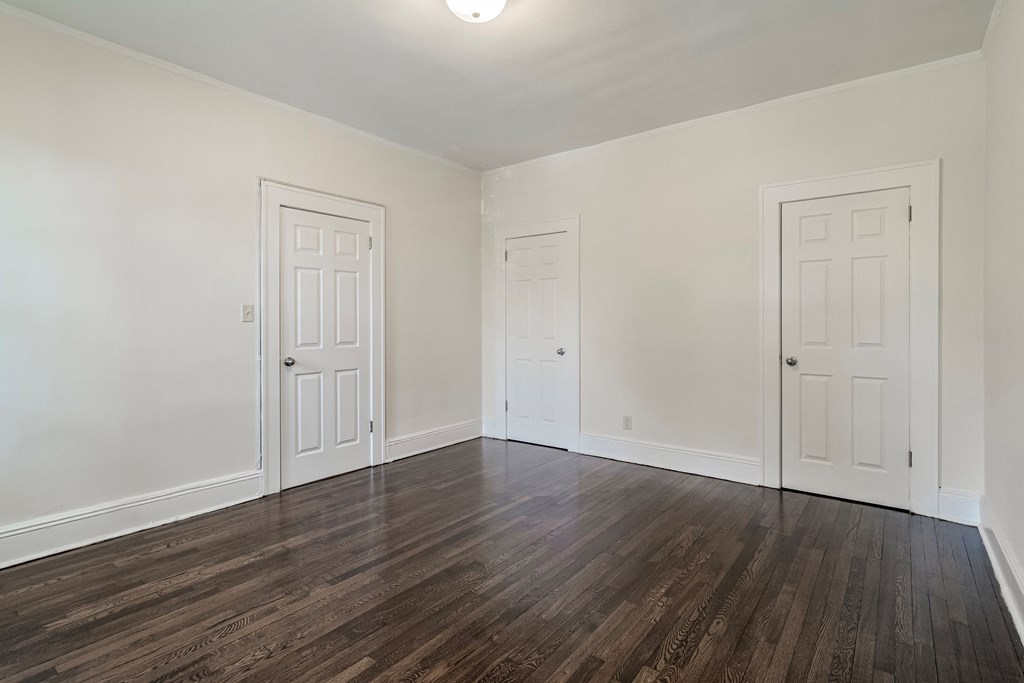 a living room with white walls and wood flooring and two doors